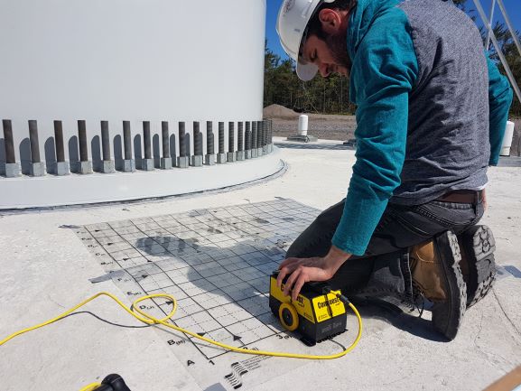 Man in hard hat using scanning device to scan and image concrete