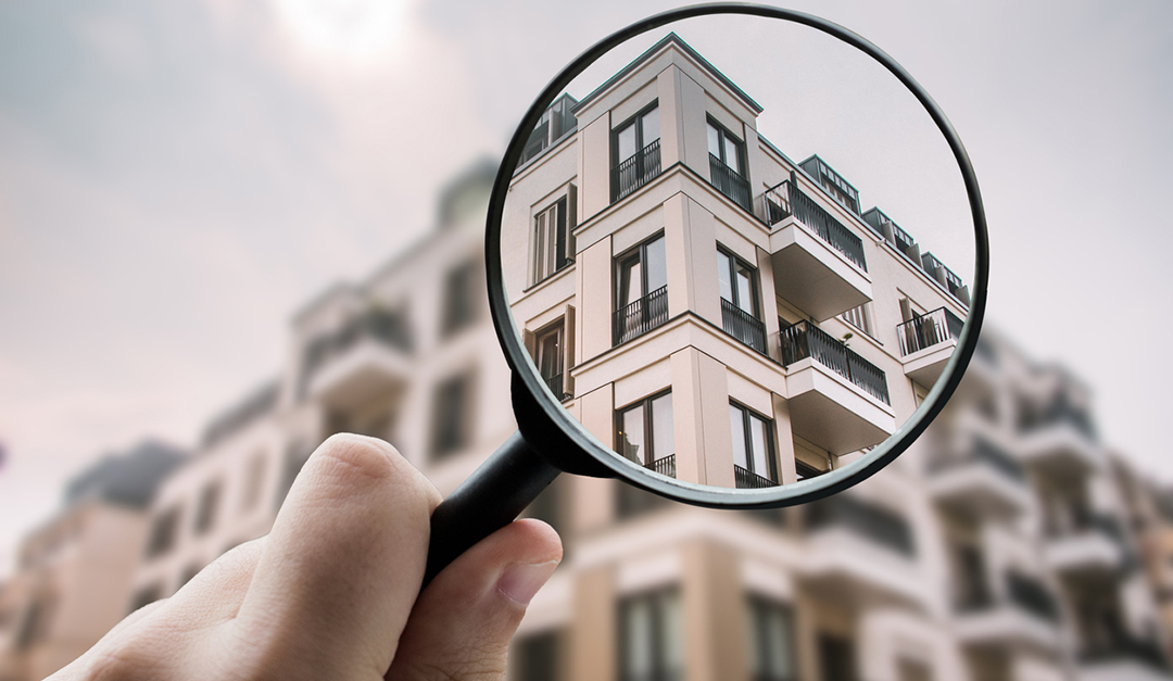 A magnifying glass over residential condo buildings in NJ representing condo building inspection