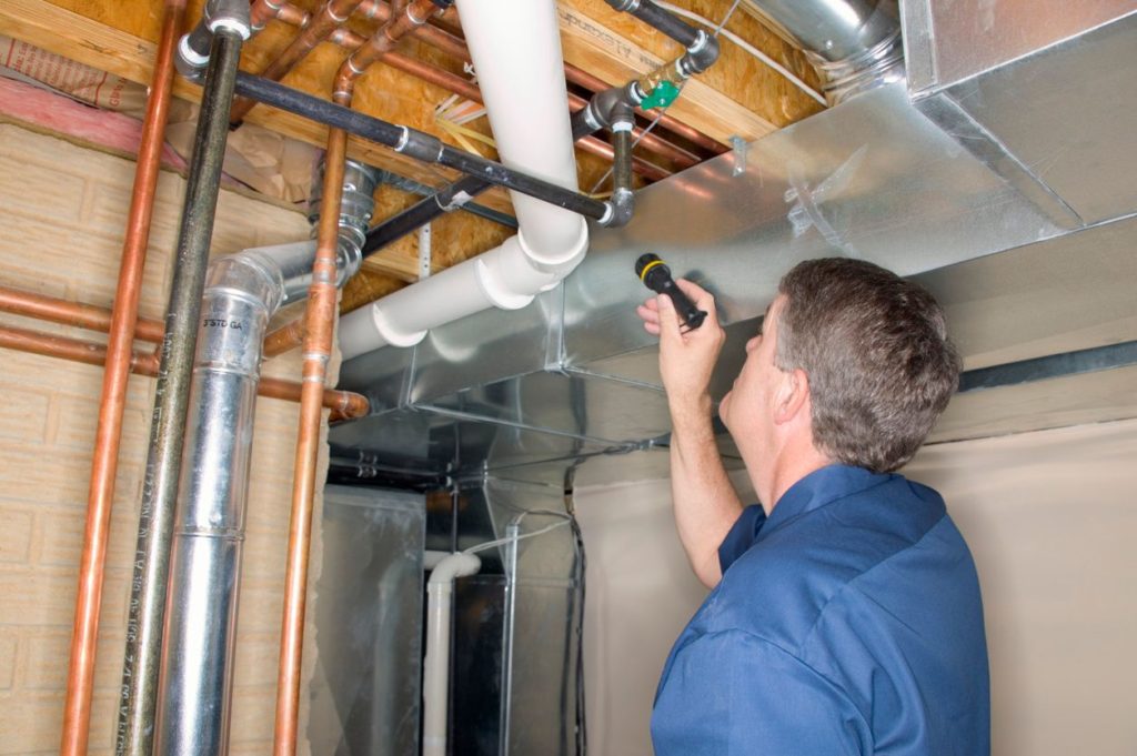 Man inspecting the ductwork of a home as part of a mechanical inspection