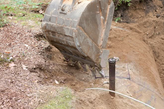 Bulldozer removing underground oil tank from property