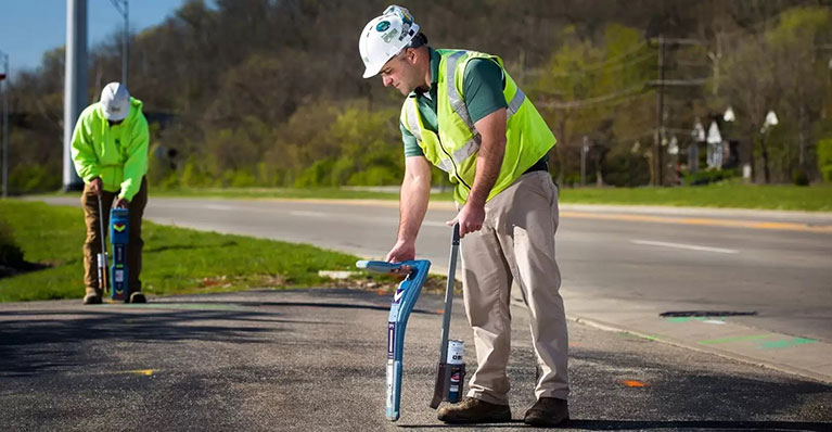 Two men using devices to scan and detect underground utilities in NJ